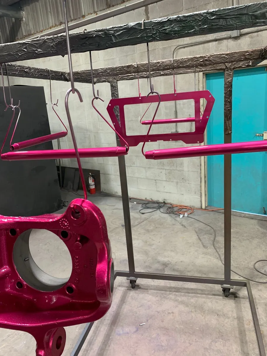 Magenta brackets and parts hanging on the coating rack